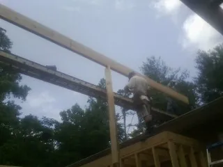 Carpenter setting a ridge beam over a new addition frame — Ice Dam Removal by Roofing Brothers in Wichita Falls