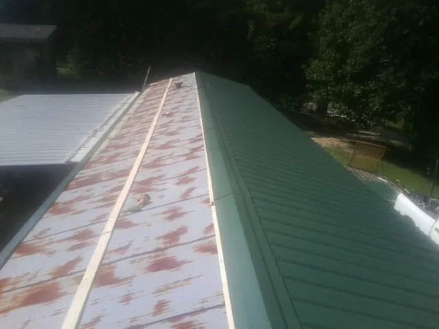 Old rusted panels beside newly installed green metal roofing — Wind Damage Roof Repair by Roofing Brothers in Wichita Falls