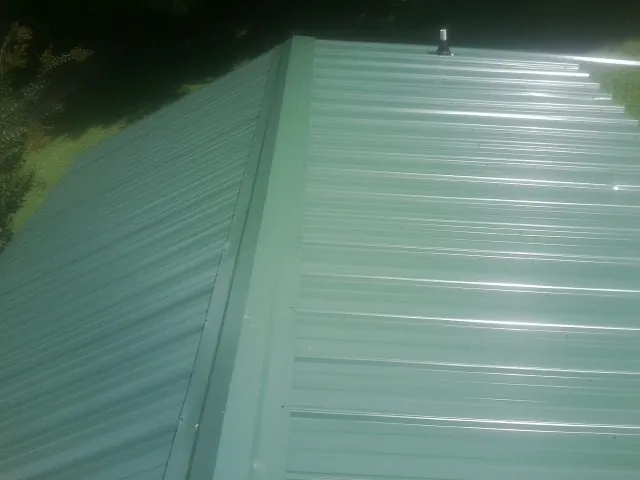 New green metal panels meeting at the ridge of a roof — Flat Roof Repair work by our crew in Wichita Falls
