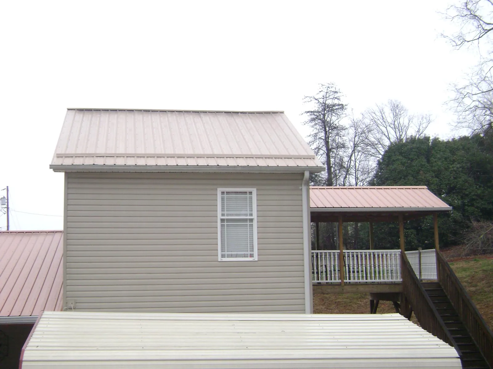 Tan metal roofs on a two story addition and attached porch, from a Roof Replacement job in Wichita Falls