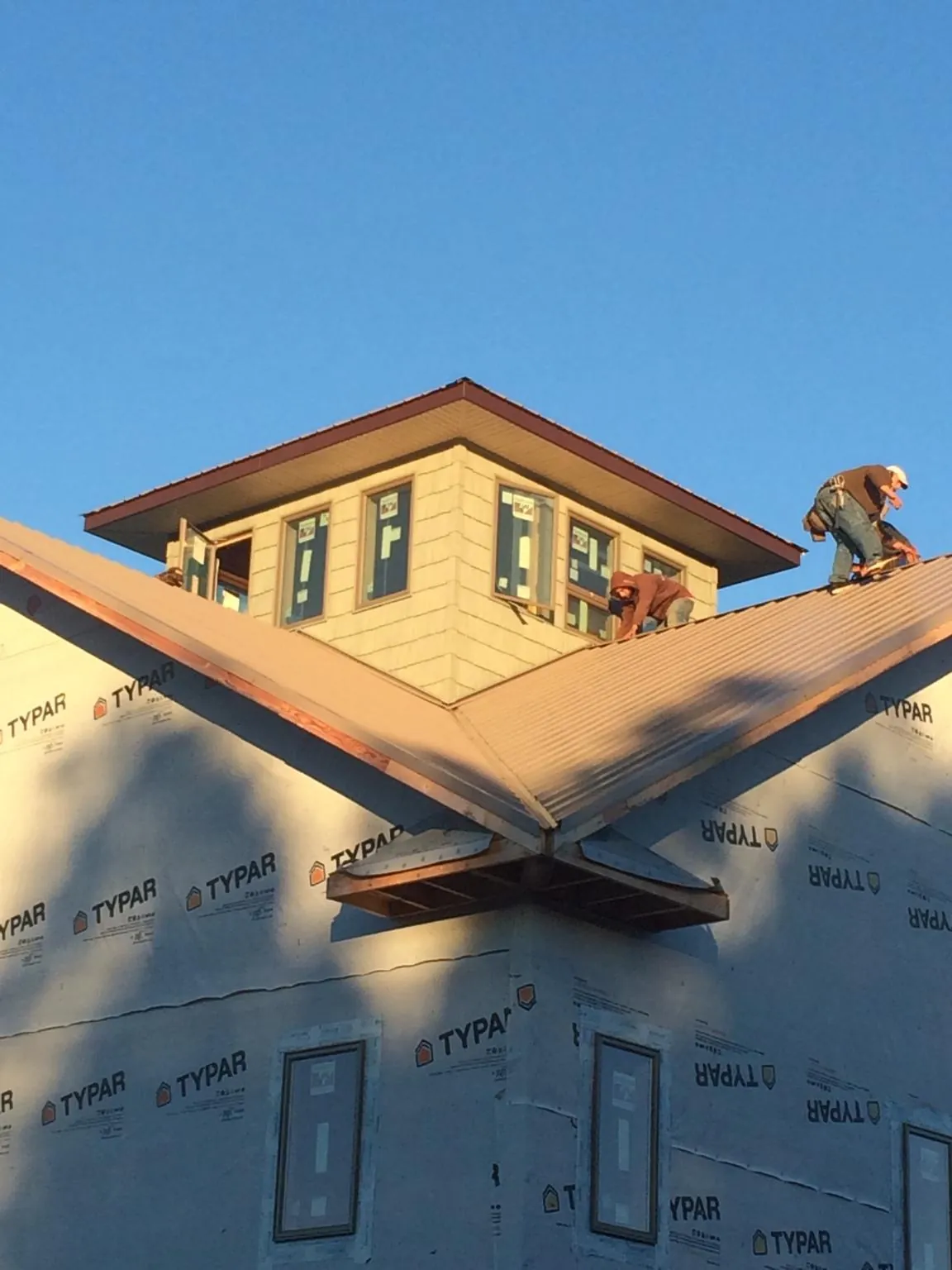 Roofers working around a rooftop cupola on a new metal roof at sunset — Roof Waterproofing in Wichita Falls by Roofing Brothers
